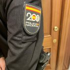 Agente de la Policía Nacional ante la puerta de una vivienda.