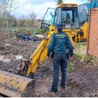 Agente de la Guardia Civil con la excavadora recuperada.