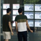 Dos jóvenes en el escaparate de una inmobiliaria