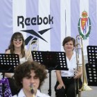 Músicos ante el panel con el escudo del club y el logo del patrocinador.