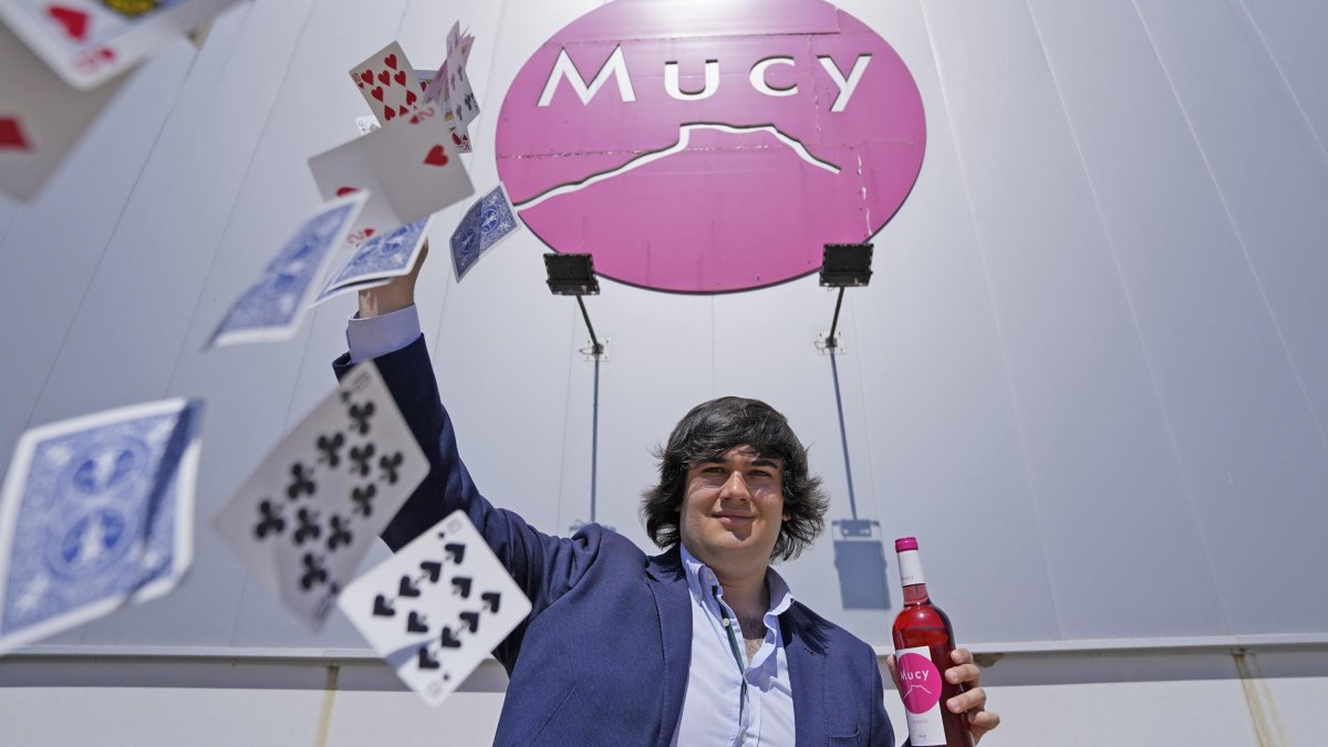 Arturo González, frente a Bodegas Mucy, con una baraja y uno de sus vinos claretes.
