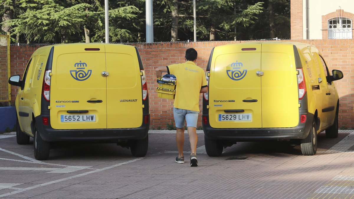 Un repartidor de Correos, en Palencia, se dispone a cargar una caja con cartas en un vehículo