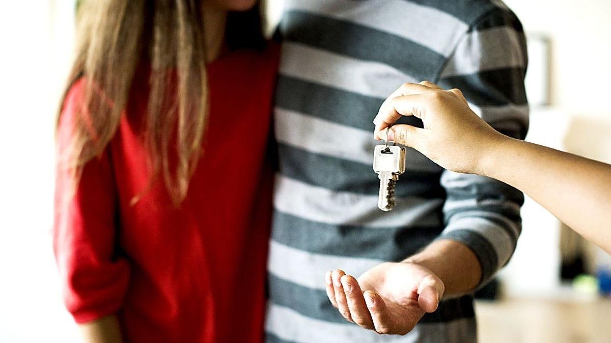 Una pareja joven recibe las llaves de su casa recién comprada.