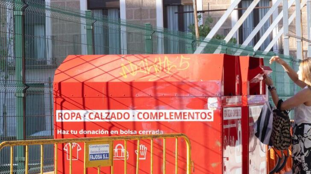 Un persona introduce ropa en un contenedor de recogida de Valladolid.