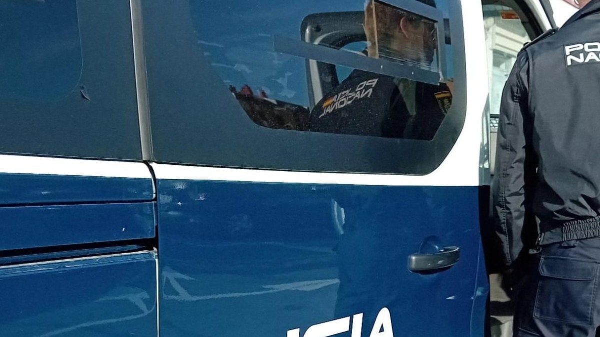 Un agente de la Policía Nacional delante de un furgón.