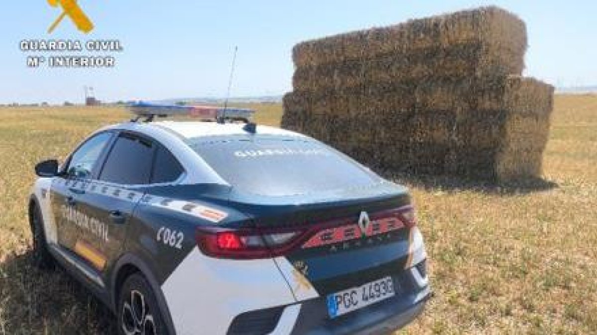Vehículo de la Guardia Civil junto a alpacas de forraje.