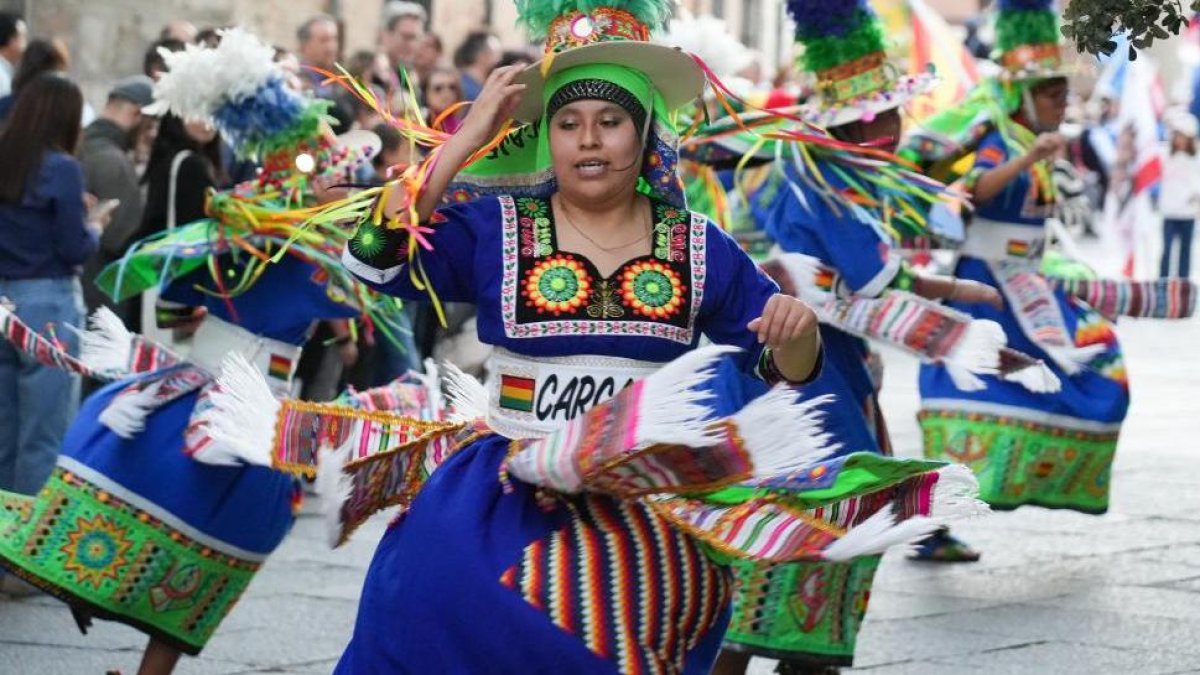 Miembros de colectivos hispanos residentes en Valladolid desfilan ante el Palacio Real ante la mirada del público.