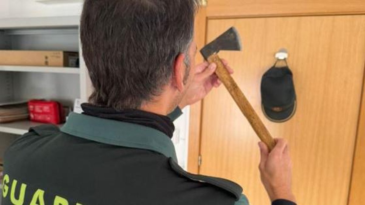 Un agente de la Guardia Civil sujeta el hacha intervenida al investigado.