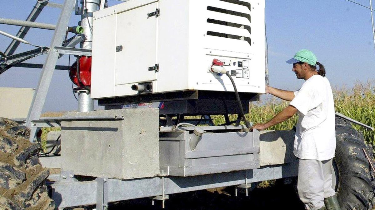Un agricultor, con un pívot de riego en una plantación de maíz, en una imagen de archivo