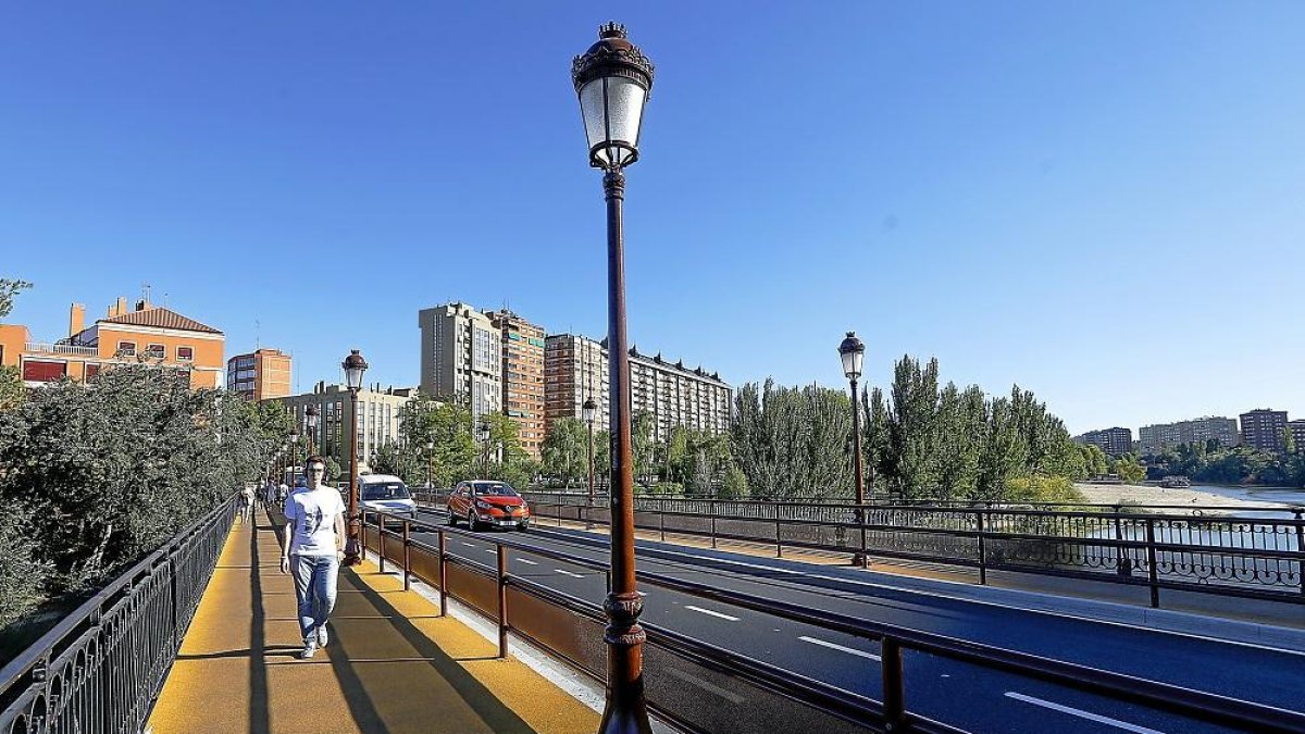 Un peatón camina por una de las aceras del puente Mayor tras cambiar el cemento por caucho.-J.M. LOSTAU