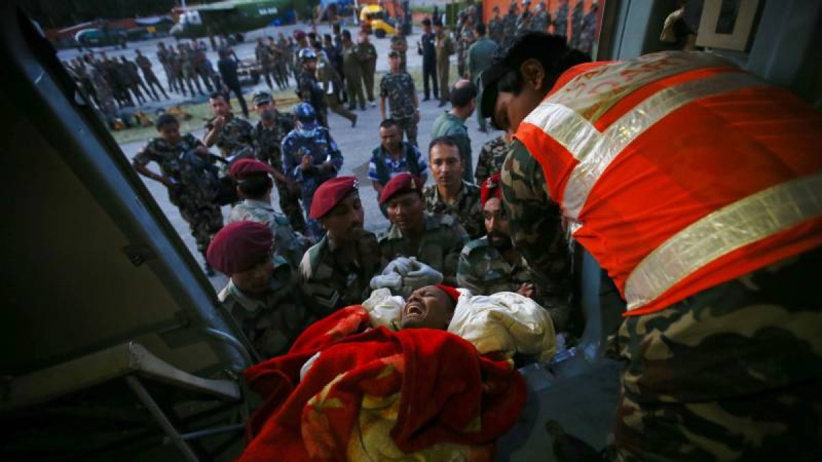 Soldados nepalíes fueron registrados este martes al trasladar a un herido, tras un terremoto de 7,3 grados en la escala Richter, en el aeropuerto de Katmandú (Nepal).-Foto: EFE