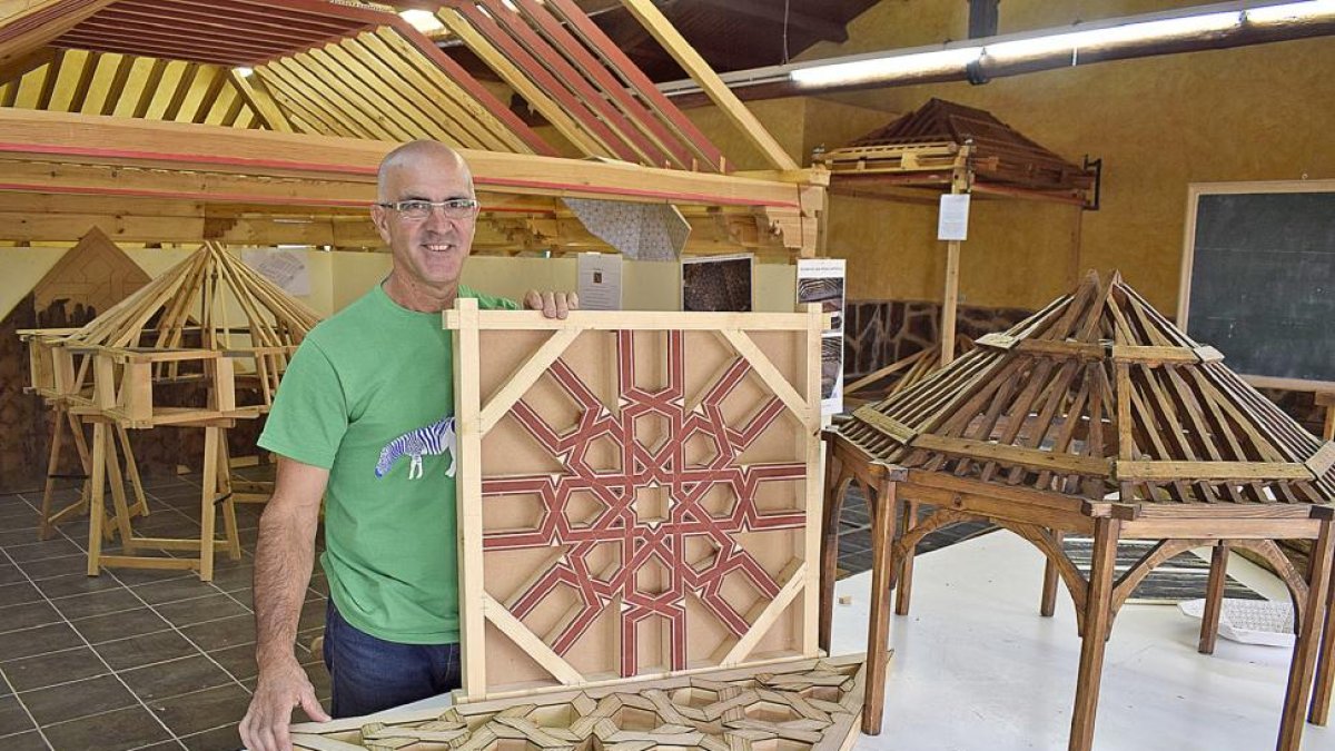 Ángel Martín, con dos taujeles -piezas decorativas de un artesonado- y una maqueta de una armadura, en el Centro de Interpretación de la Carpintería Mudéjar de Narros del Castillo (Ávila), donde imparte clases prácticas sobre esta especialidad.-ARGICOMUNICACIÓN