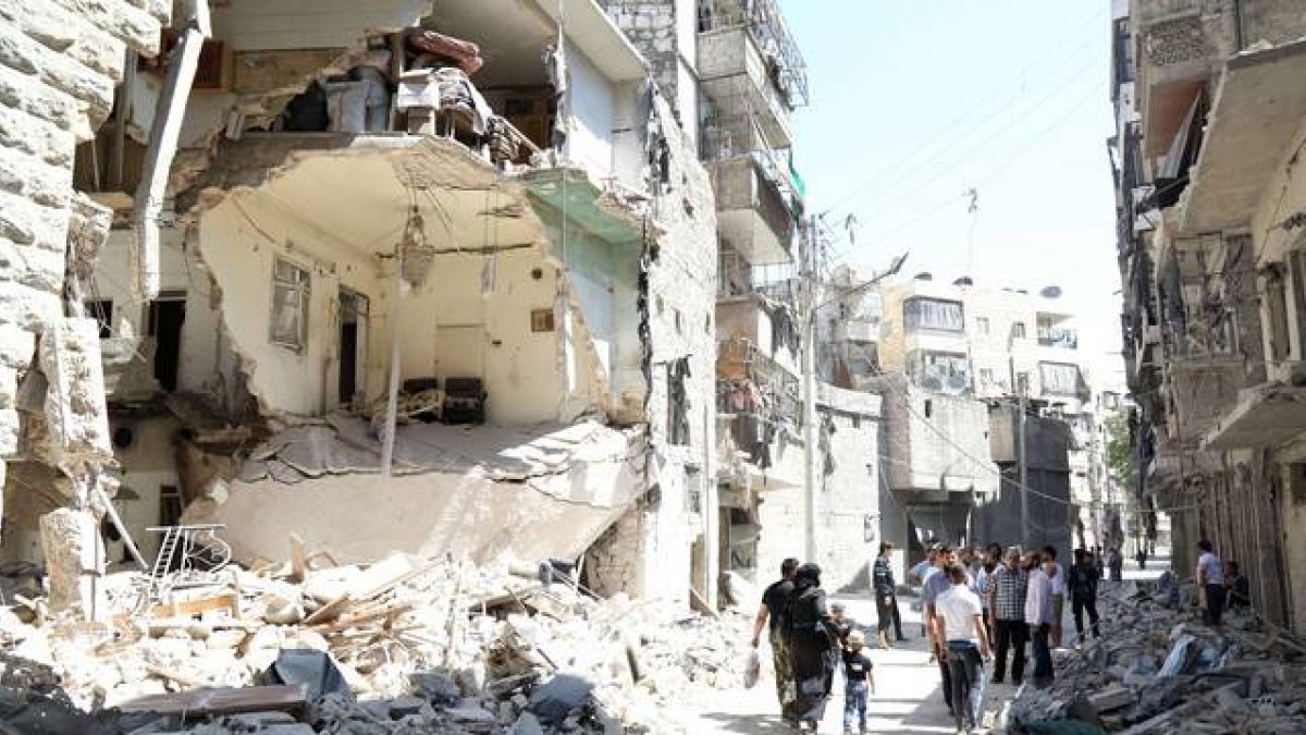 Vecinos de Alepo pasan junto a un edificio destruido en un bombardeo del régimen, este domingo.-Foto: KHALED KHATEB / AFP / JALED JATEB