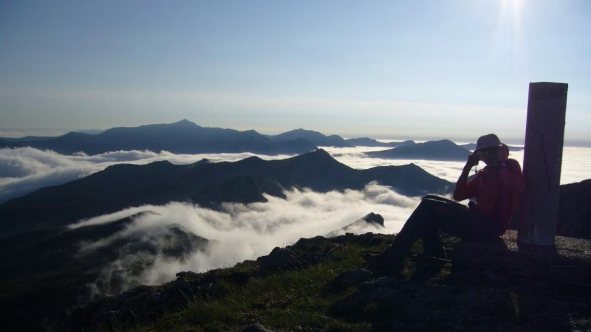 Un montañero fotografía el paisaje con el mar de nubes desde el vértice geodésico del Pico La Chana.-I.M.