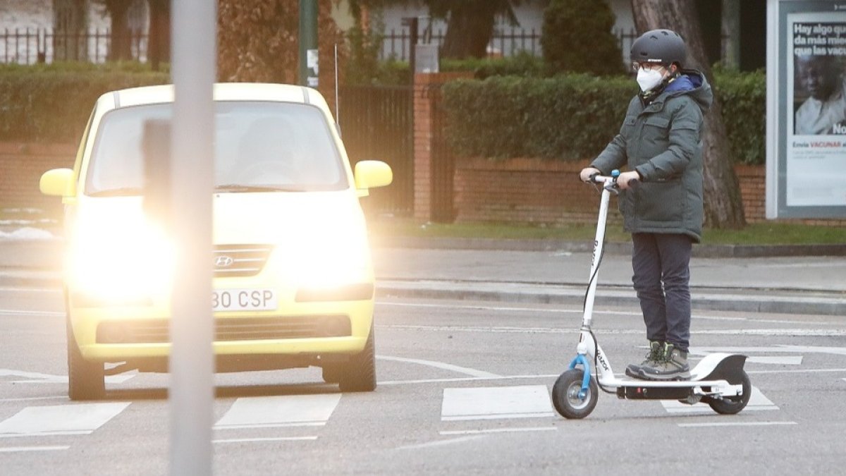 Un joven con un patinete cruza un paso de peatones en una calle de Valladolid. J.M. LOSTAU