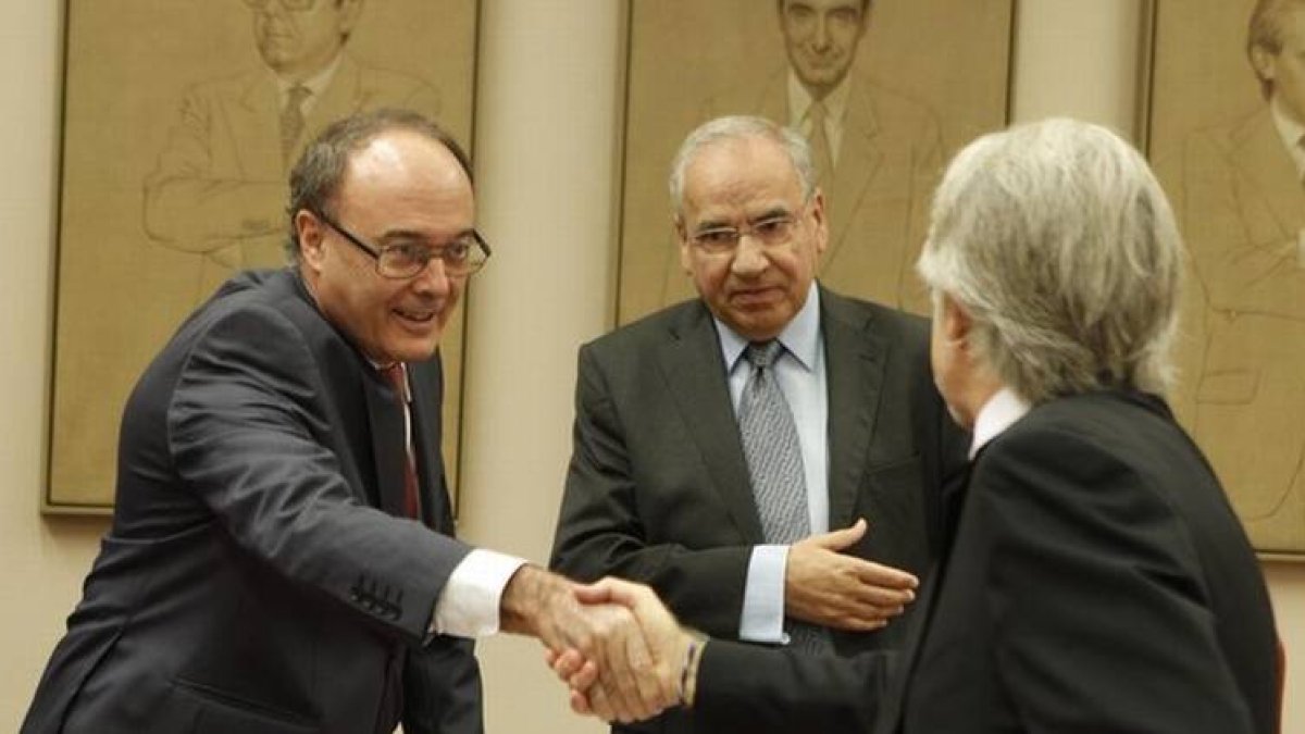 Luis María Linde saluda a Josep Sánchez Llibre delante de Alfonso Guerra, en la Comisión de Presupuestos.-Foto: AGUSTÍN CATALÁN