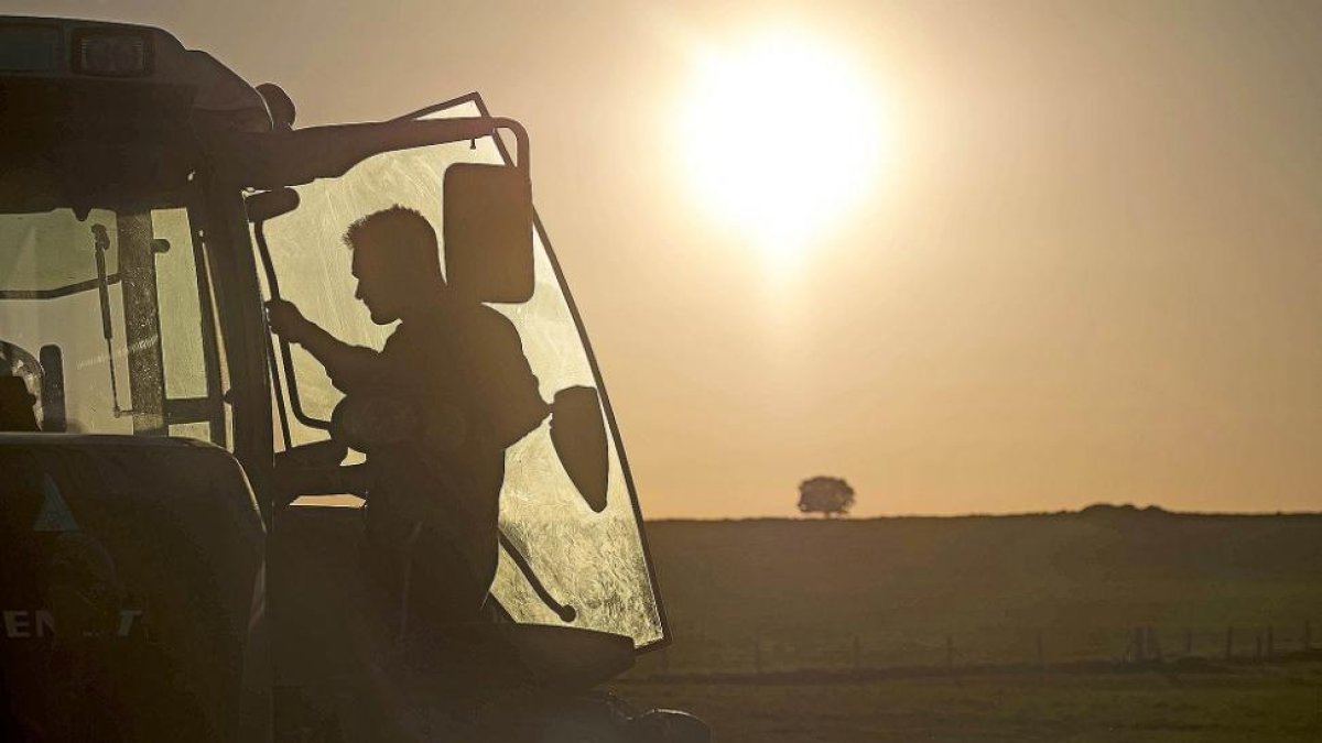 Joven agricultor subiendo a su tractor al atardecer coincidiendo con el final de la jornada laboral.-ENRIQUE CARRASCAL