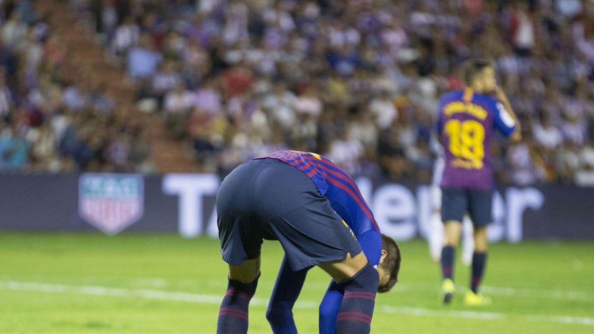 El defensa central azulgrana Piqué coloca uno de los numerosos trozos de césped levantados durante el Real Valladolid-Barcelona.-MIGUEL ÁNGEL SANTOS