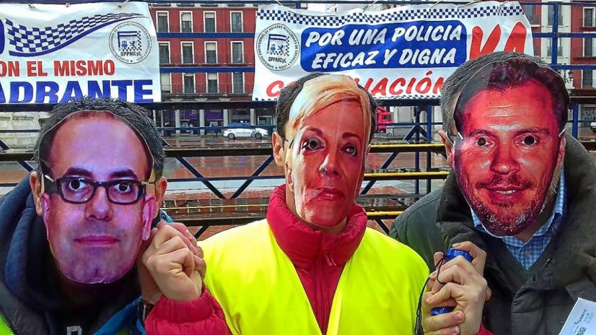 Tres agentes con las caretas de Vélez, de la jefa de la Policía, Julia González, y de Puente durante la protesta del martes.-E. M.