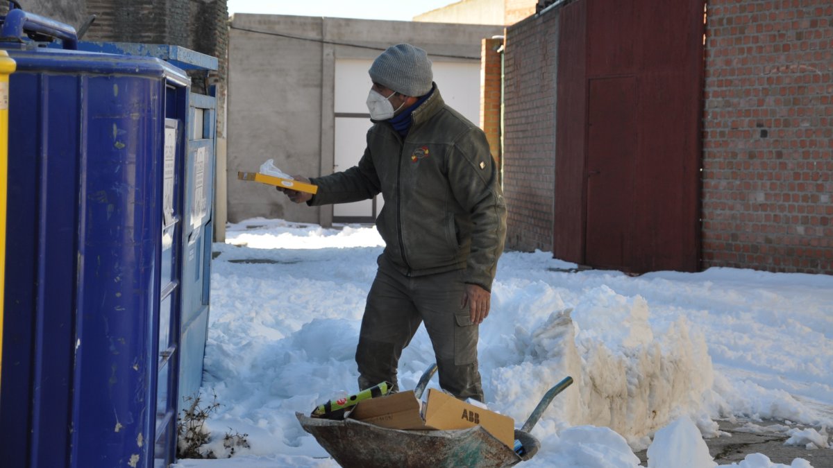 Un vecino de Fuente del Sol tira cartones al contenedor rodeado de nieve. SANTIAGO G. DEL CAMPO