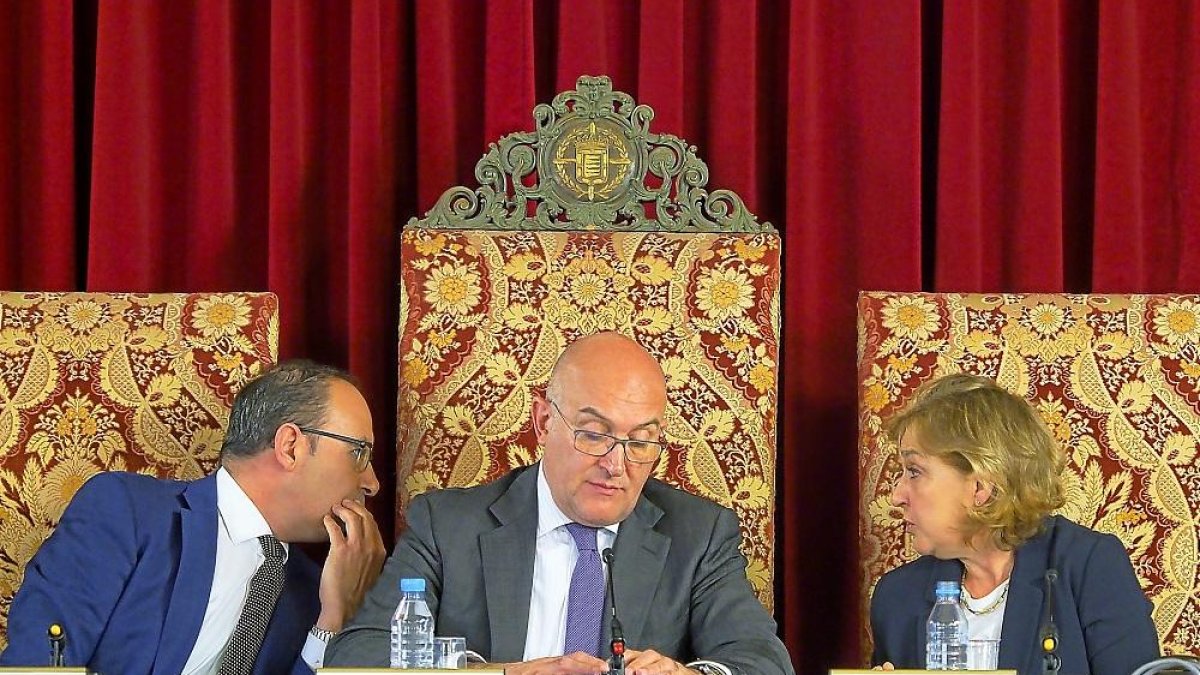 Jesús Julio Carnero consulta su móvil en el Pleno de ayer, mientras Víctor Alonso le susurra a Carmen Lucas.-E. M.