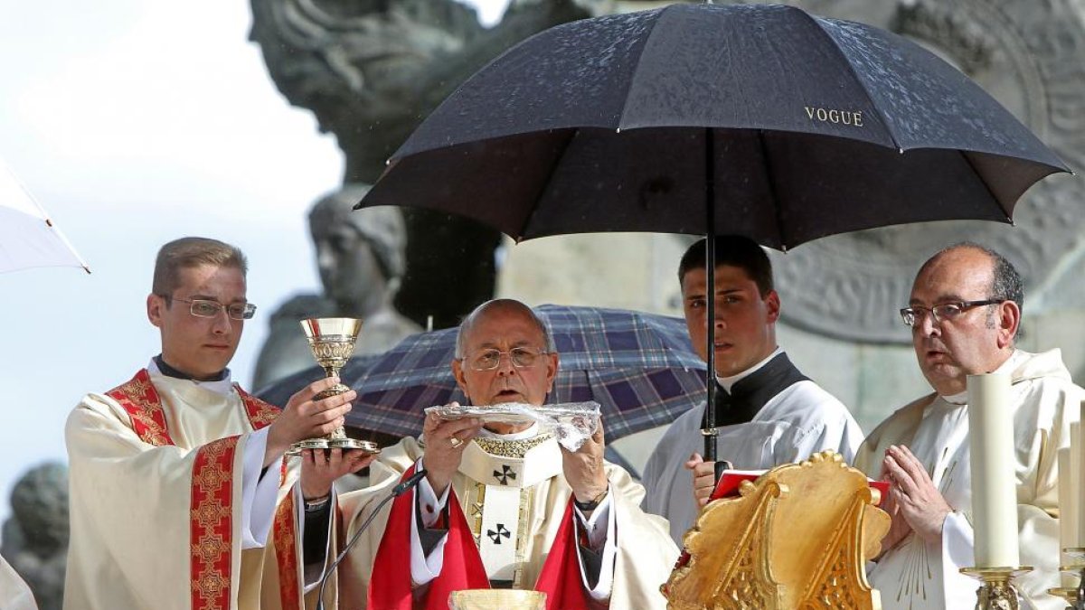 El cardenal arzobispo de Valladolid, Ricardo Blázquez, consagra el Pan y el Vino bajo un paraguas ayer, en la misa del Corpus-J. M. LOSTAU