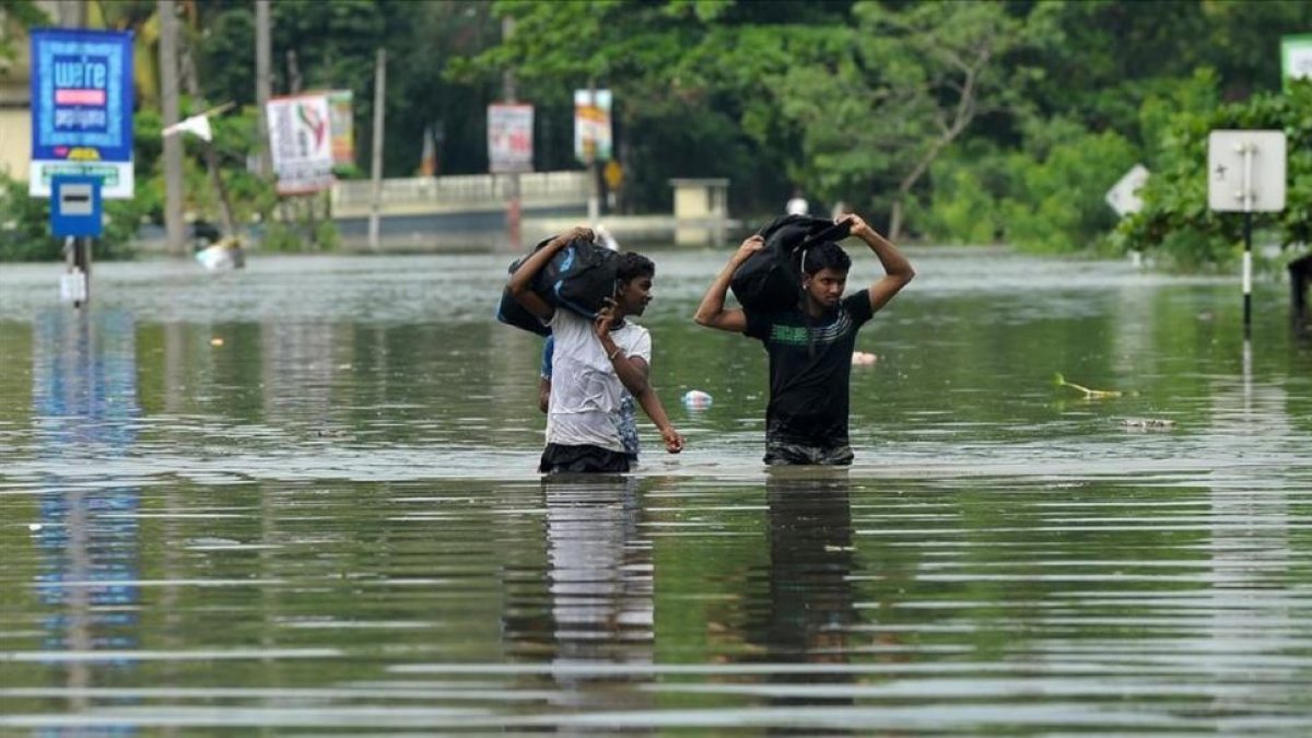 Dos jóvenes caminan entre las aguas a unos 17 kilómetros de la capital de Sri Lanka, Colombo.-ISHARA S KODIKARA