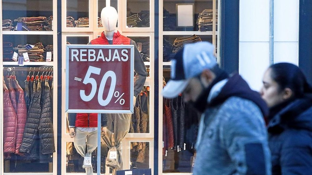Dos personas pasan por delante de un comercio del centro de Valladolid, en una imagen de archivo.
