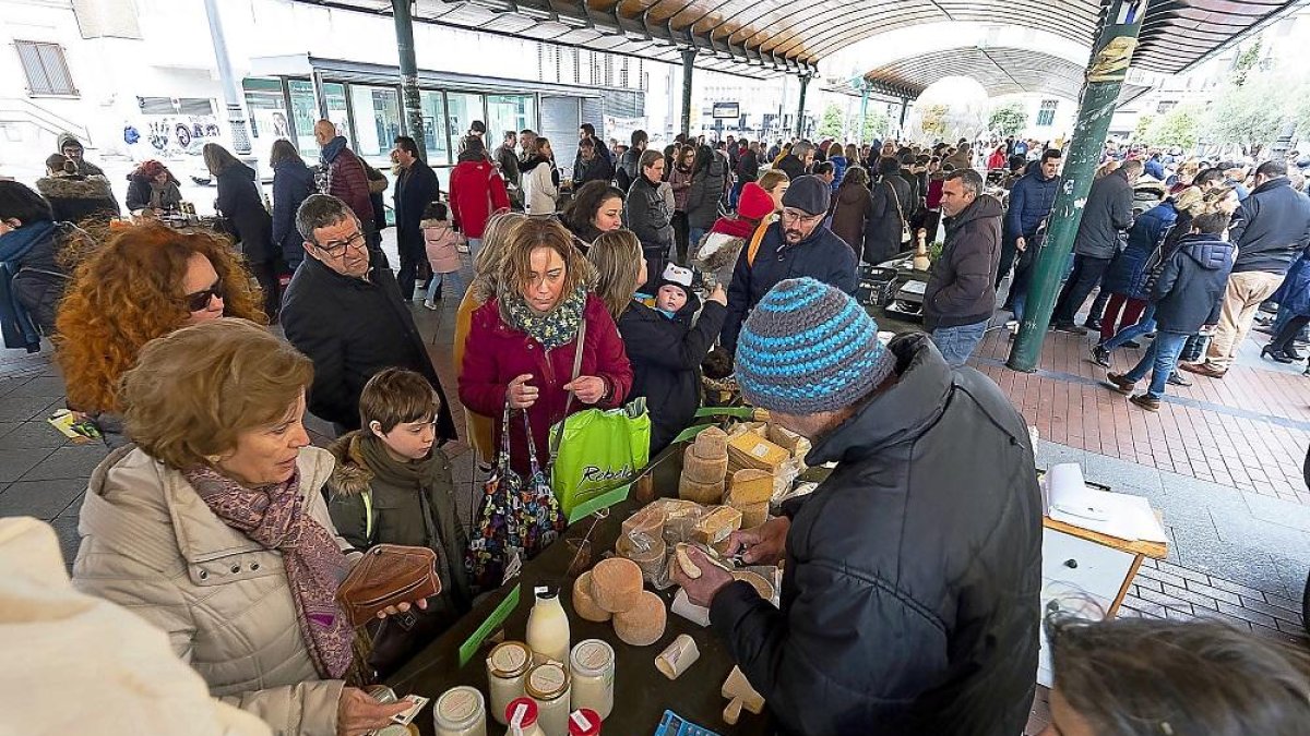 Varios clientes compran en el puesto de quesos del Ecomercado de plaza España.-PABLO REQUEJO
