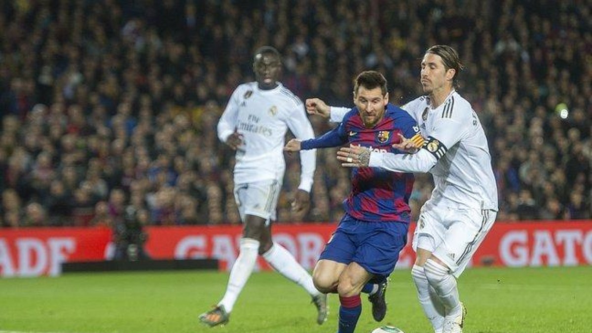 Messi y Sergio Ramos pelean por un balón.-JORDI COTRINA