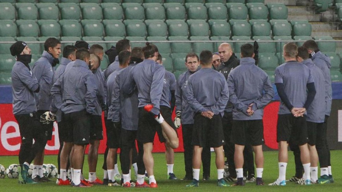 Los jugadores del Madrid escuchan a Zidane en el entrenamiento en el Ejército Polaco, campo del Legia.-AP / CZAREK SOKOLOWSKI