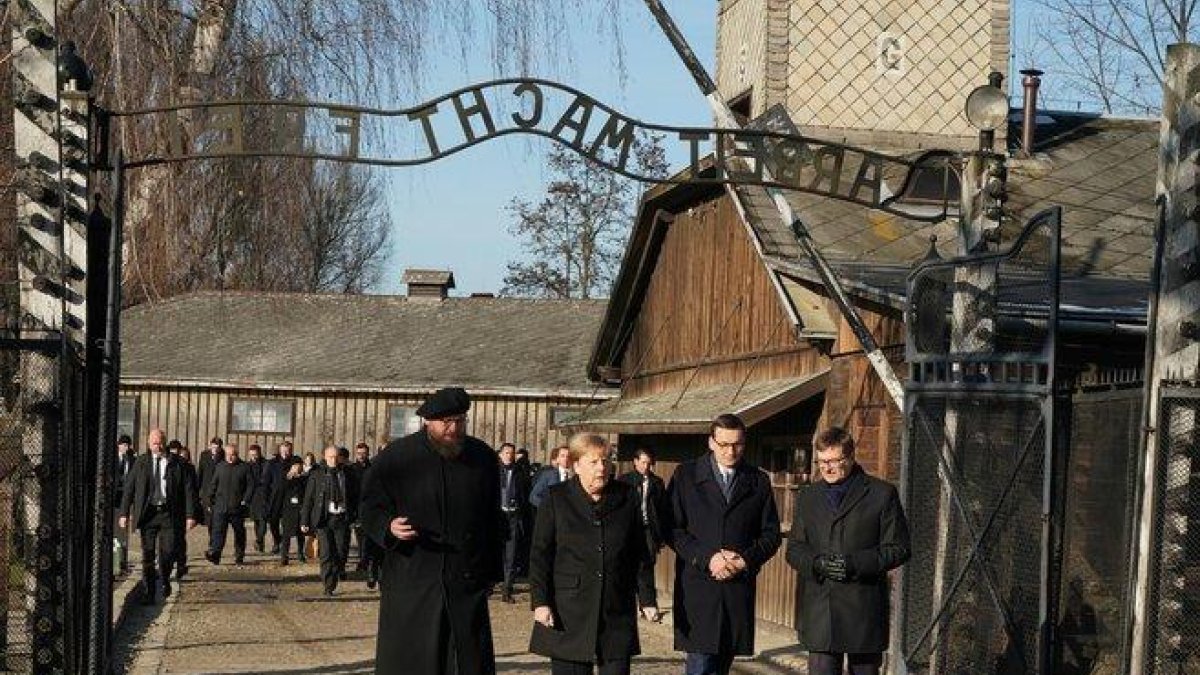 Angela Merkel cruza la puerta de entrada del campo de concentración de Auschwitz, bajo el siniestro cartel ’El trabajo os hará libres’.-AFP