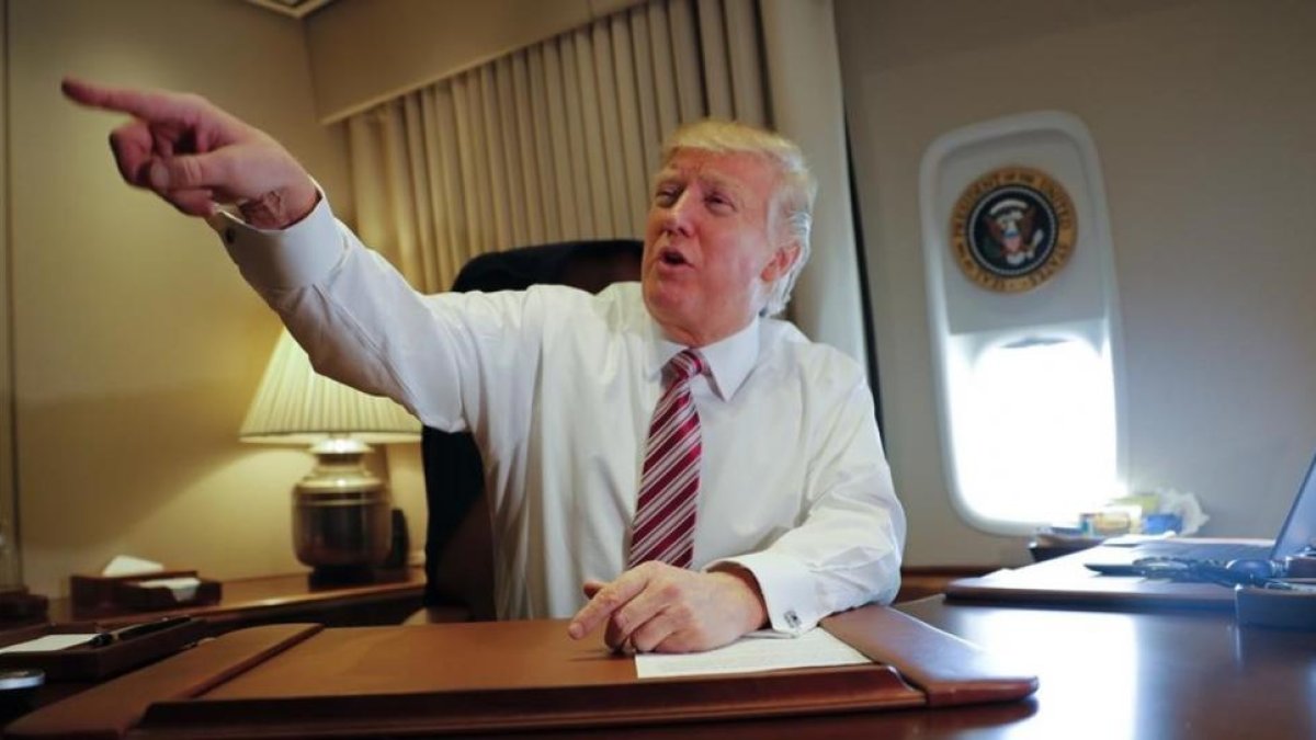 Trump señala a miembros de la prensa, sentado en su despacho del Air Force One, el 26 de enero.-AP / PABLO MARTINEZ MONSIVAIS