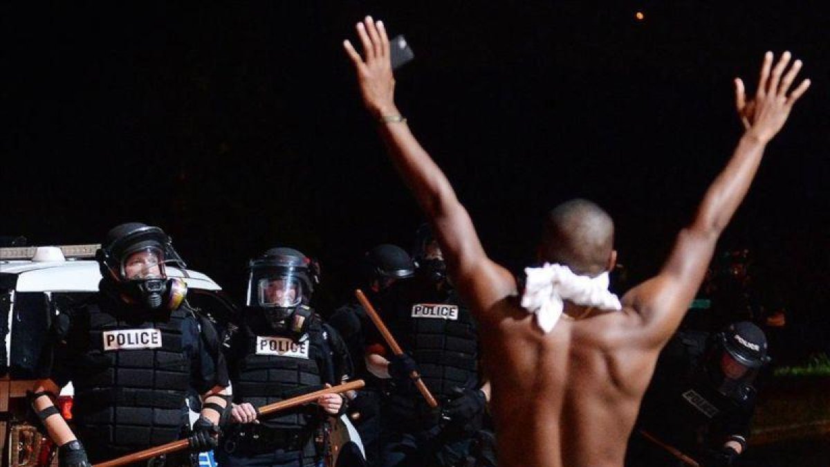 Un joven levanta los brazos ante la policía en Charlotte.-JEFF SINER / AP