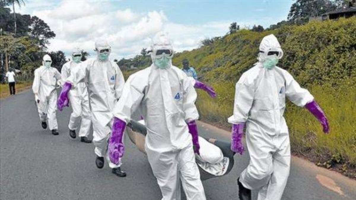 Personal protegido con trajes especiales retira el cuerpo de un fallecido por ébola en Monrovia (Liberia).-Foto: AP / ABBAS DULLEH