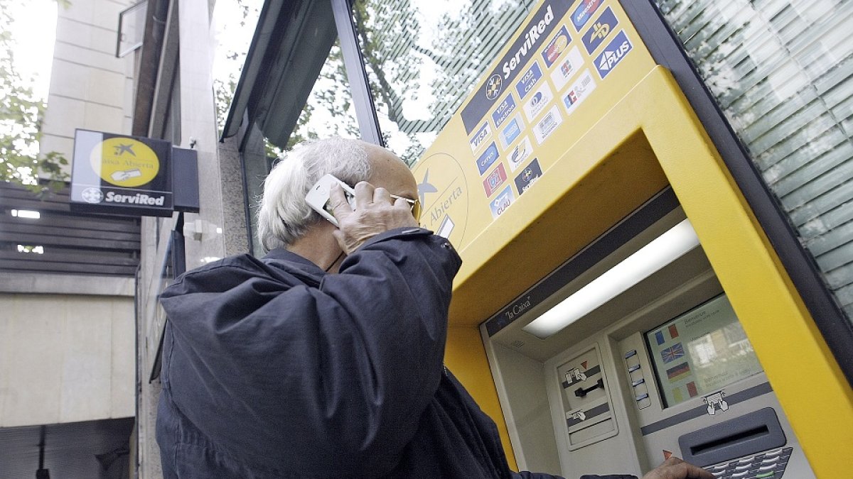 Una persona mayor utiliza el cajero automático de una sucursal bancaria.- ALBERTO CUELLAR