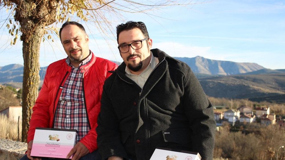Los hermanos Marcos y Daniel López sentados frente a su obrador de pastelería con el paisaje de la sierra de Gredos a su espalda.-