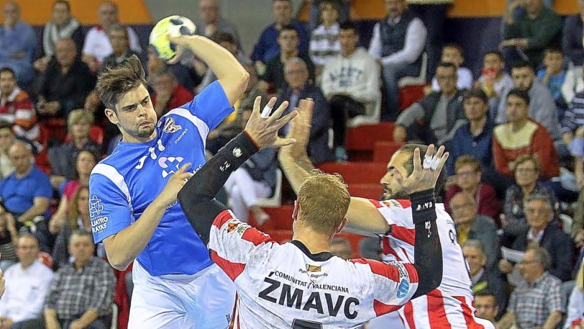 Rubén Río arma el brazo en un lanzamiento en suspensión desde nueve metros ante la oposición de dos jugadores del Puerto Sagunto.-PHOTO-DEPORTE