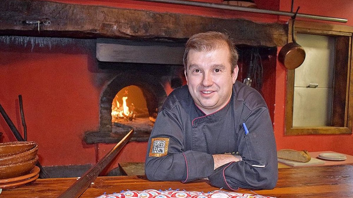 Sergio Blázquez, junto a la boca del horno de asar, con contraetiquetas de lechazo asado.-ARGICOMUNICACIÓN