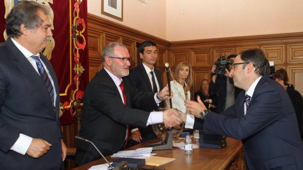 El recién elegido alcalde de Palencia, Alfonso Polanco, recibe el bastón de mando de manos del concejal de mayor edad, el socialista Jesús Merino.-Ical