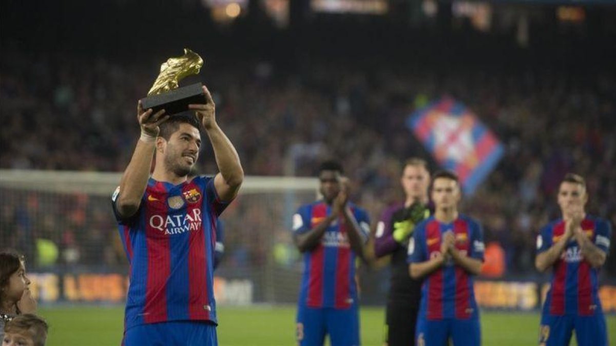 Luis Suárez exhibe el Balón de Oro conquistado de la temporada 2015-16 a la hinchada del Barça en el Camp Nou.-JORDI COTRINA