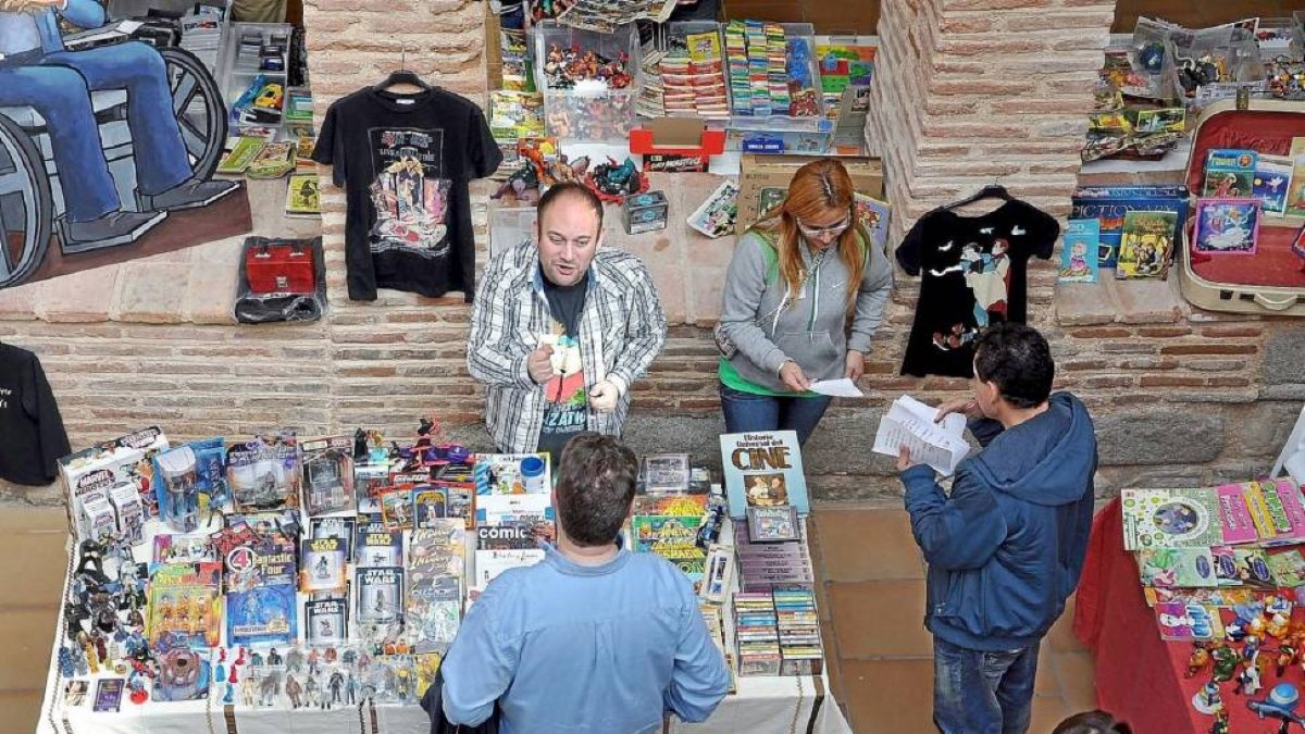 Visitantes de la Feria de Mitomanías y Aficiones buscan ediciones singulares en un expositor de cómics.-ICAL