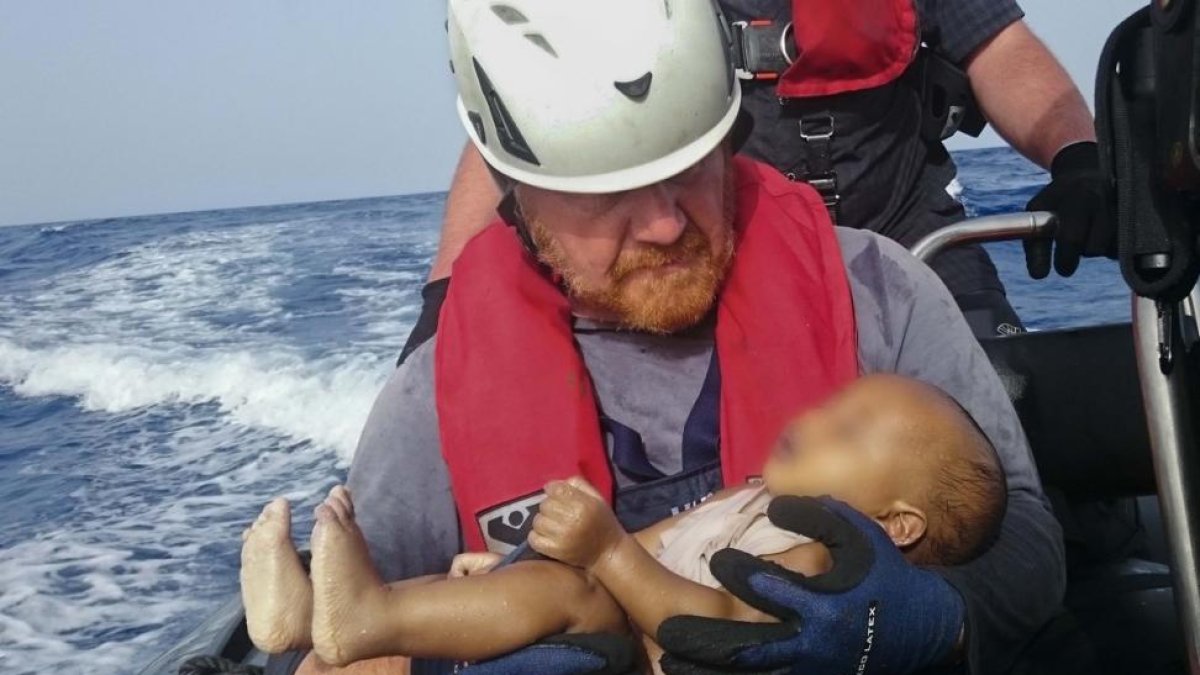 El bebé ahogado en los brazos del socorrista alemán Martin.-AP / CHRISTIAN BUTTNER