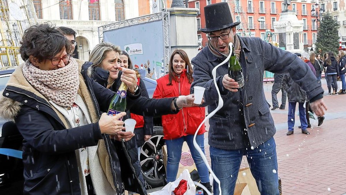Rubén Cerrato descorcha una botella de champagne en la plaza Mayor ante la mirada de su mujer Teresa.-J.M. LOSTAU