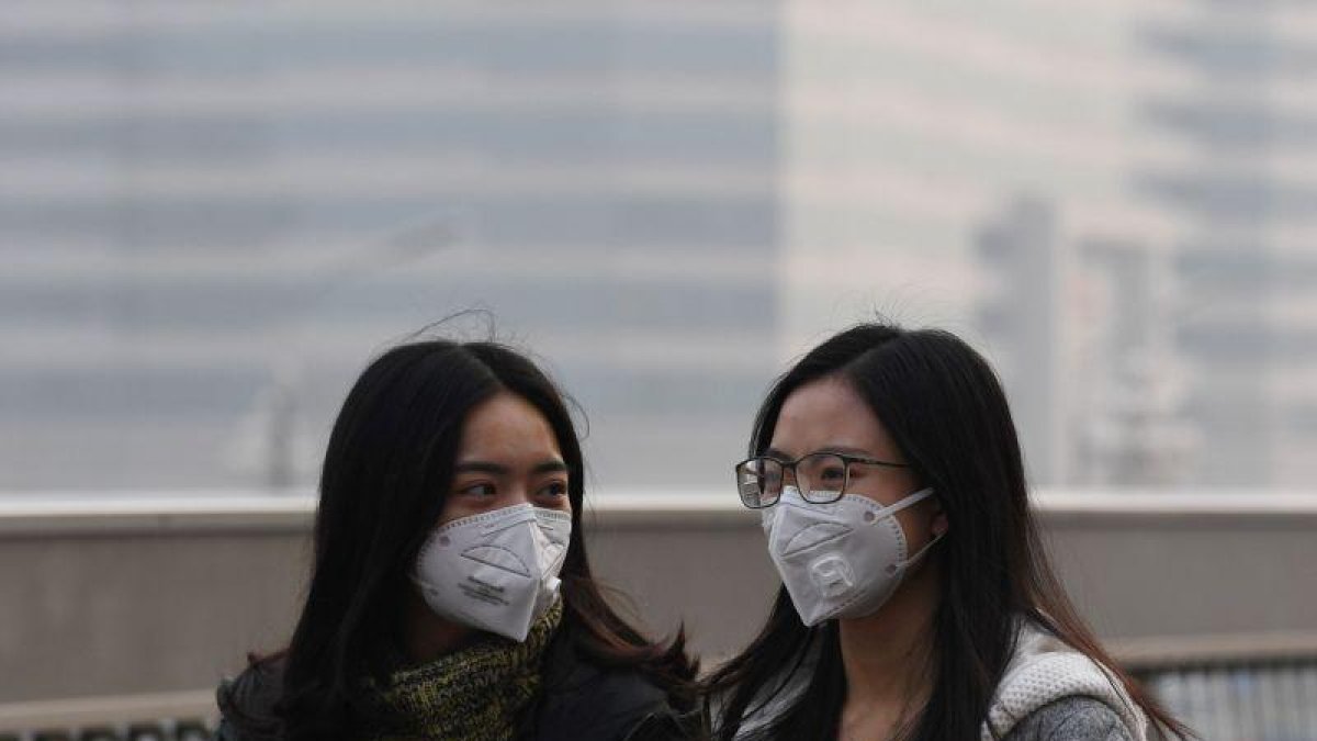 Dos chicas se protegen de la contaminación en Pekín el pasado lunes.-AFP / GREG BAKER
