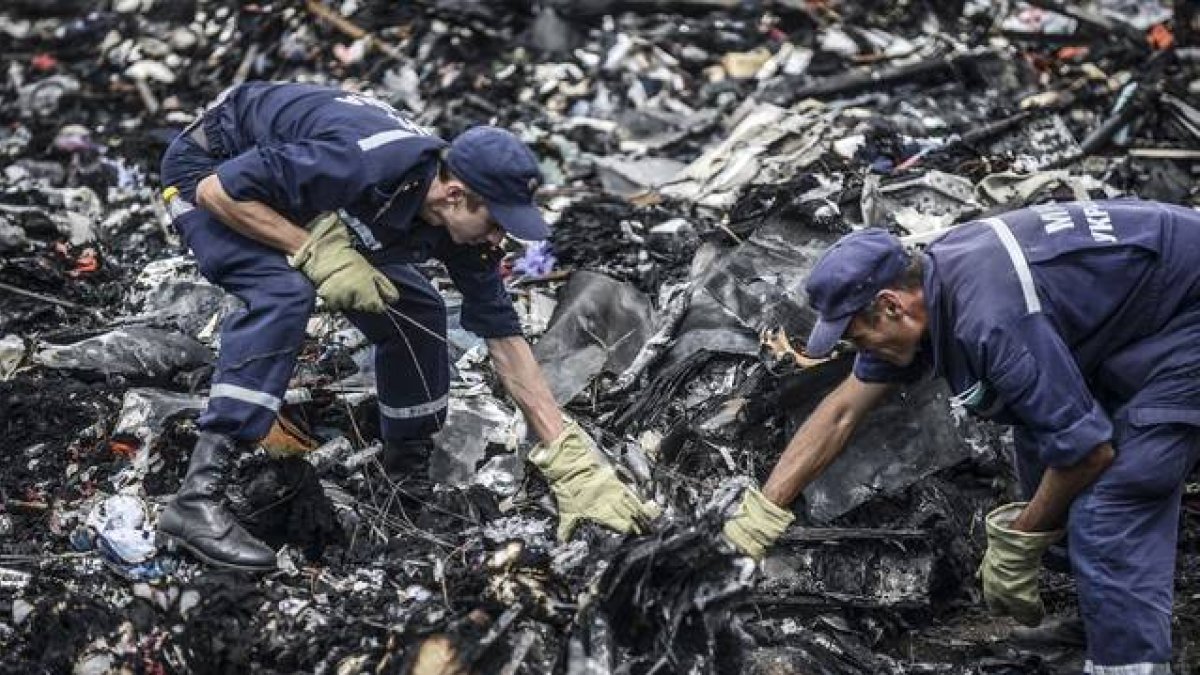 Dos agentes buscan entre los restos del vuelo MH17 de Malaysia Airlines, el pasado 20 de julio en Donetsk (Ucrania).-Foto: AFP / BULENT KILIC