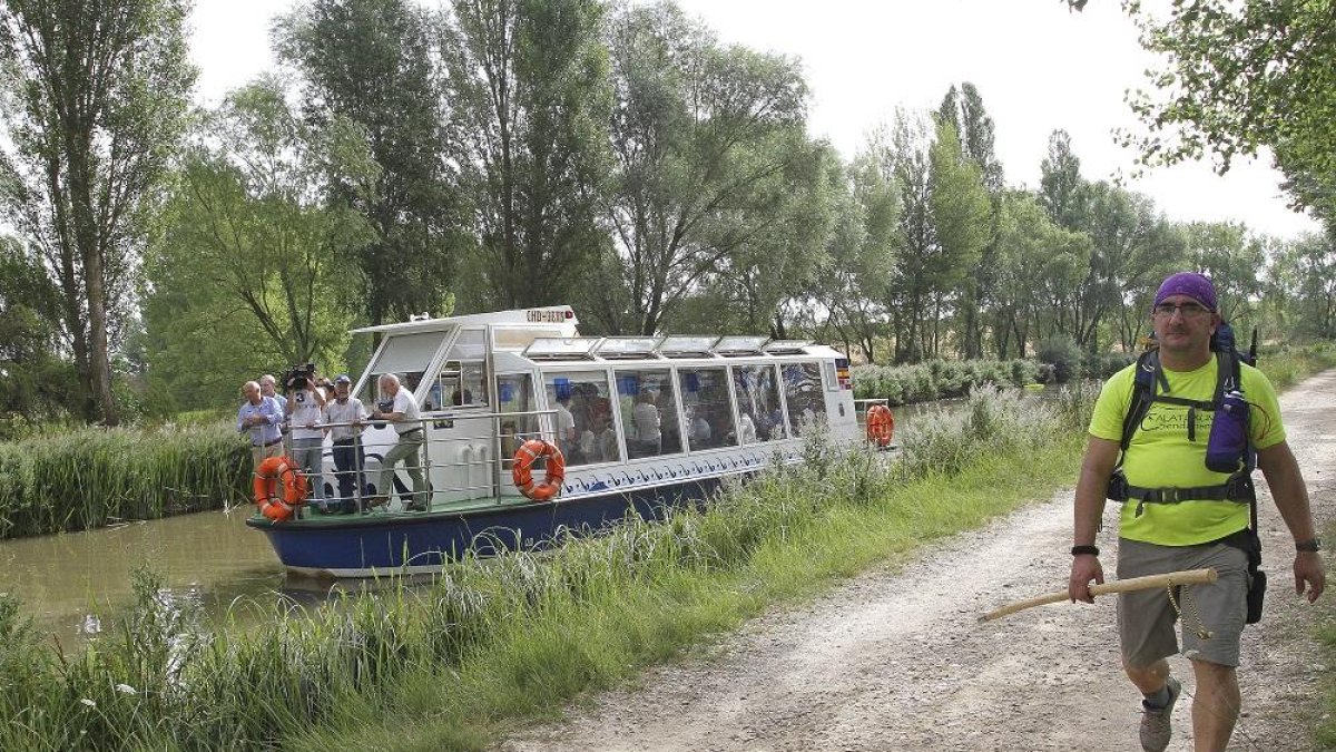 Un peregrino realiza un tramo de la Ruta Jacobea por el Camino Francés, a la orilla del Canal de Castilla, junto a la embarcación Juan de Homar.-MANUEL BRÁGIMO
