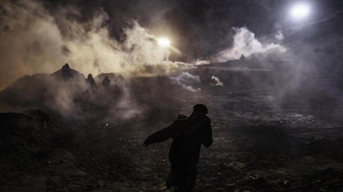 Migrantes envueltos en una nube del gas lanzado por las patrullas fronterizas de EEUU.-EL PERIÓDICO