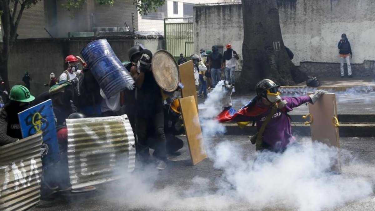 Manifestantes chocan con las fuerzas de seguridad chavistas durante una marcha en Caracas, el 1 de mayo.-AP / ARIANA CUBILLOS
