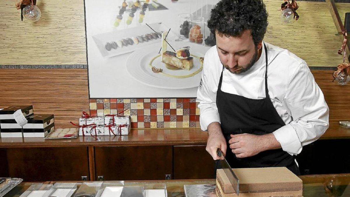 El pastelero Julián Arranz corta una porción de turrón artesano en el mostrador del obrador de Pedrajas de San Esteban.-J.M. LOSTAU